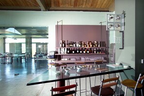 A modern bar area with a glass table, bar stools, and a wine rack with various bottles.