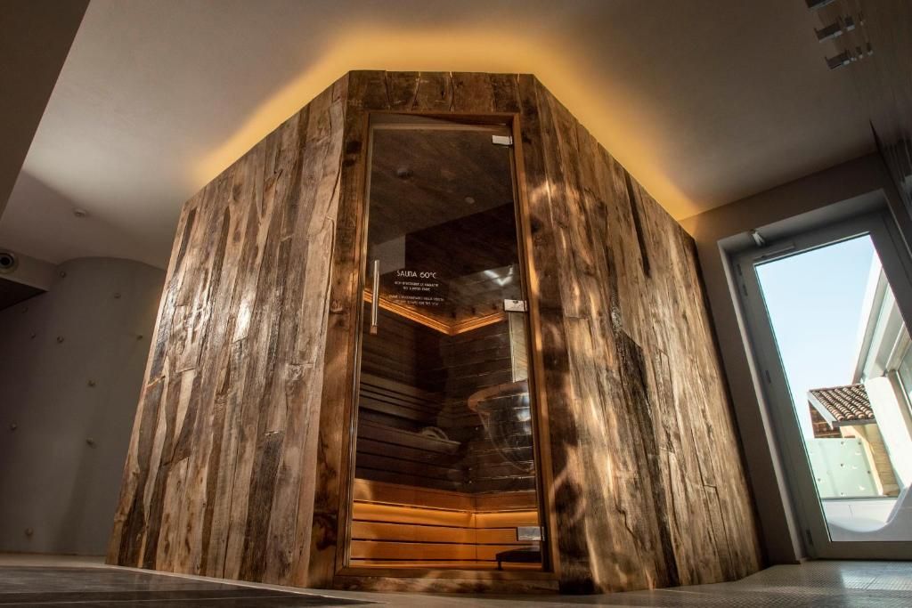 Una sauna con revestimiento de madera y puerta de vidrio, mostrando un letrero que indica una temperatura de 50°C.