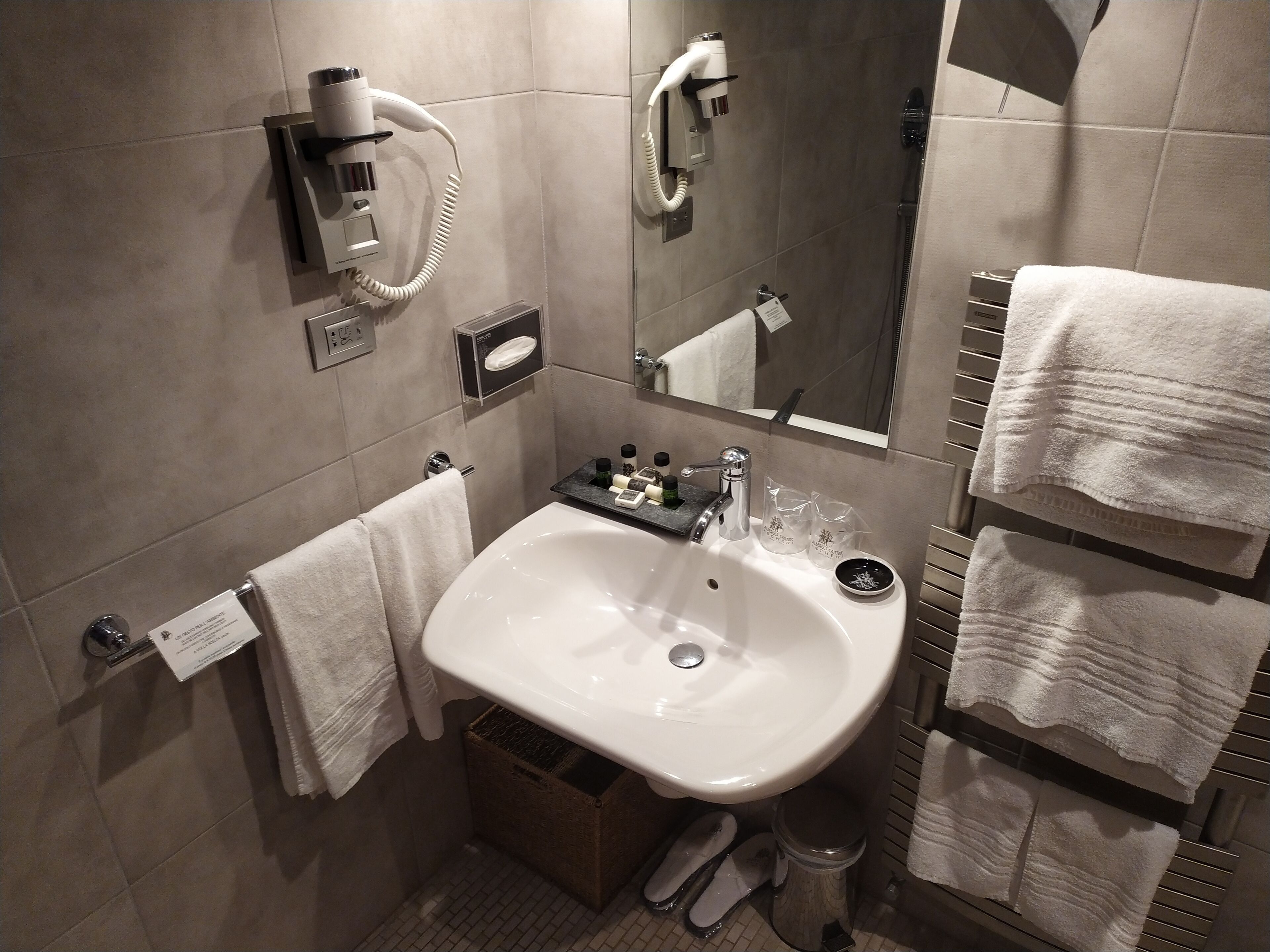 Ein modernes Badezimmer mit Waschbecken, Handtuchhalter und Wandhaartrockner.