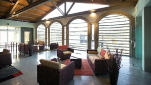 Un hall amplio con techos altos, ventanas arqueadas grandes y mobiliario de mimbre.