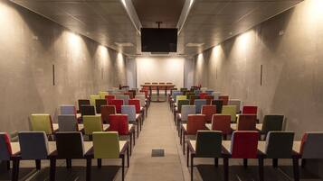 Une salle de conférence avec des rangées de chaises et un grand écran à l’avant.