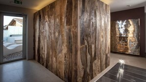 Un interior moderno con un gran muro de acento de madera, una obra de arte metálica en la pared y vistas de un cuarto con bañera.