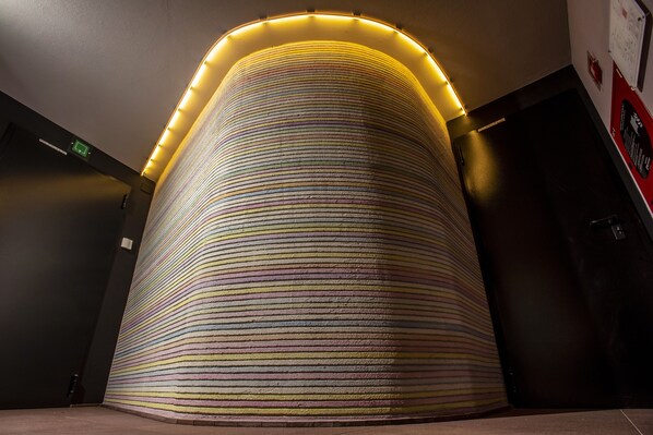 A curved wall with a striped pattern and a light strip at the top.