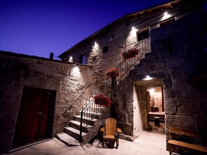 A stone building with a staircase leading to a second floor, a wooden door, and a bench. - Aldea Rural Pazos De Arenteiro (Boboras)