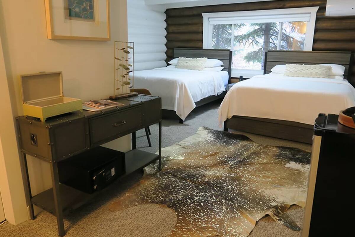 A bedroom with two beds, a desk, and a rug with a unique pattern.