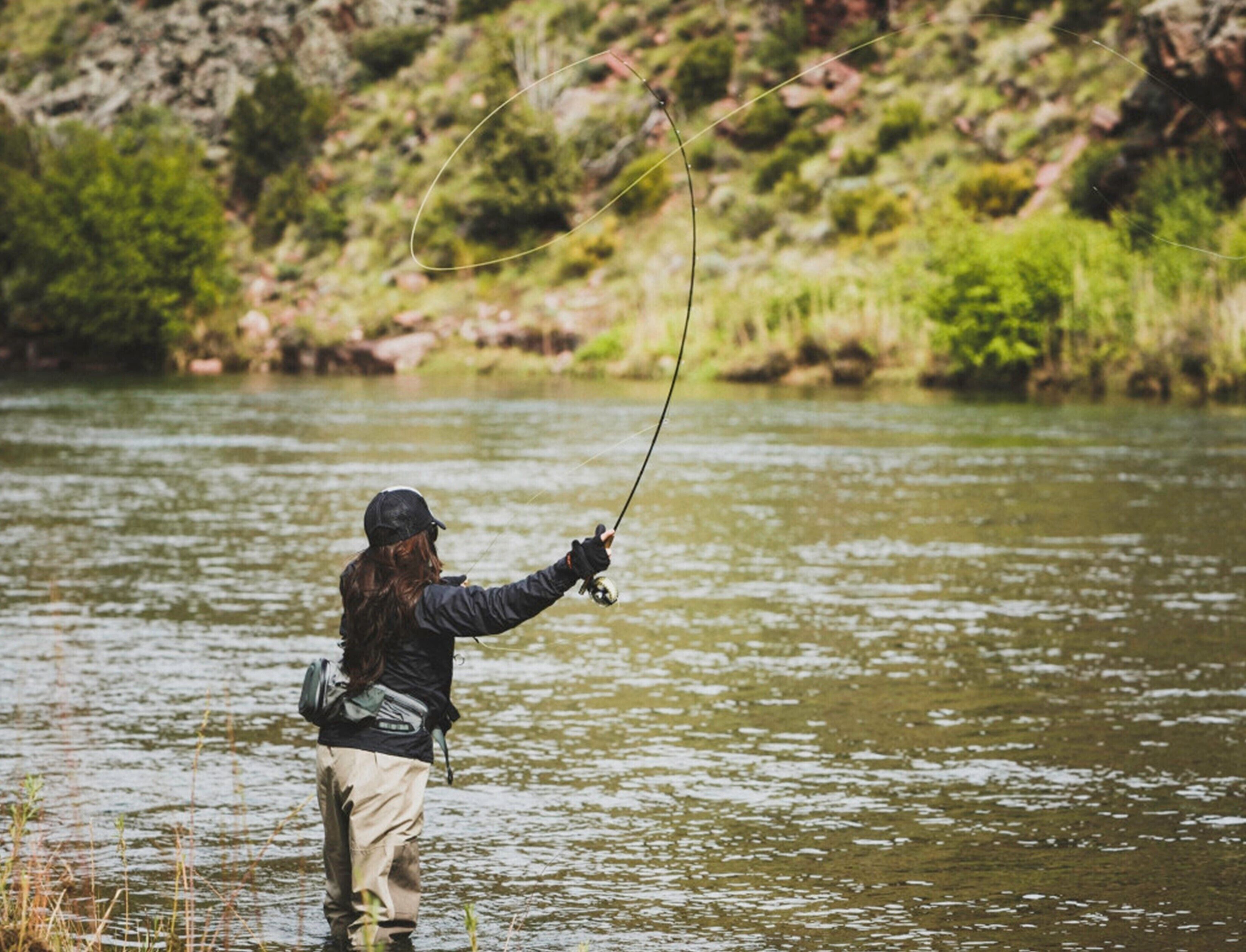 A person standing in a river, holding a fishing rod.