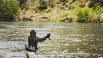 A person standing in a river, holding a fishing rod.