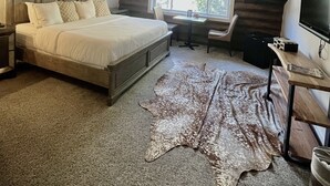 A bedroom with a large bed, a desk, and a TV. - Alaskan Inn (Ogden)