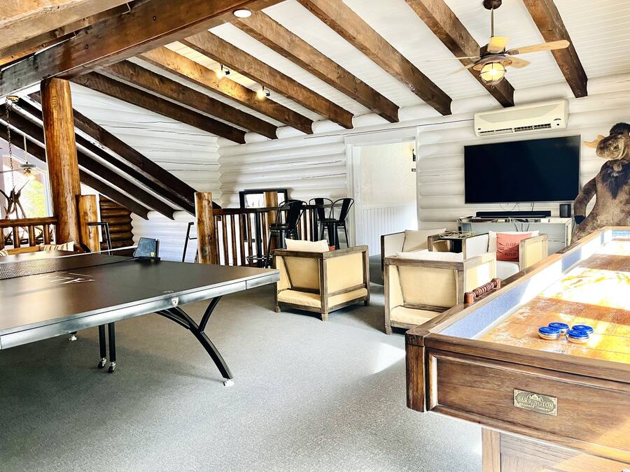 Una habitación acogedora con mesa de billar, asientos cómodos, televisor y ventilador de techo.
