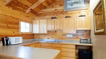 Cocina estilo cabaña de madera con una isla grande, armarios de madera, un microondas, un tostador y un fregadero.