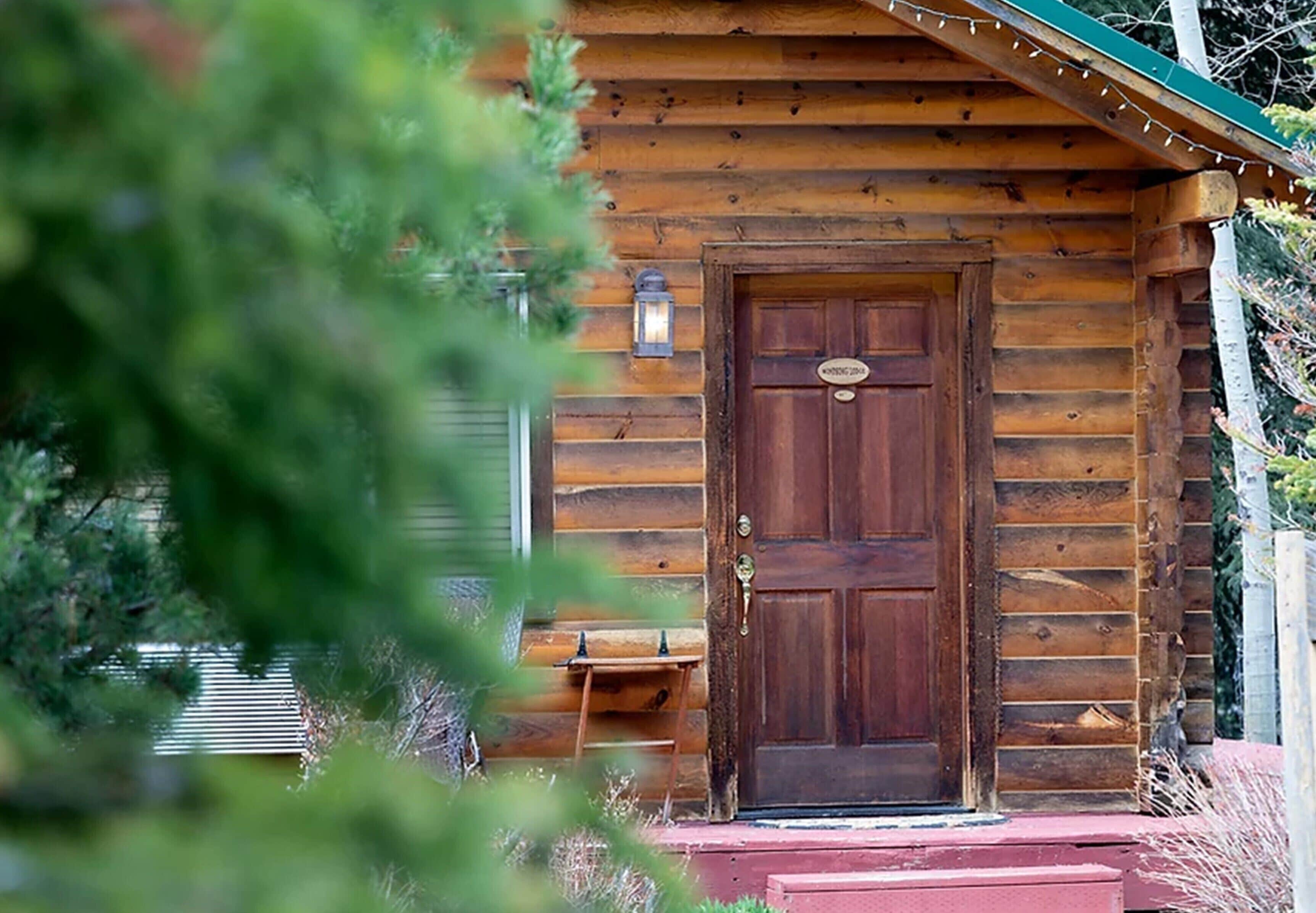 Une cabane en bois avec une porte d’entrée bien visible, un petit porche et une boîte aux lettres.