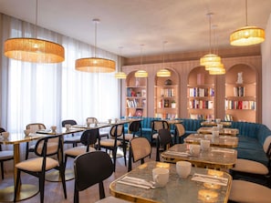 Un espace de détente moderne, aménagé comme une bibliothèque, avec des tables, des chaises et des étagères.