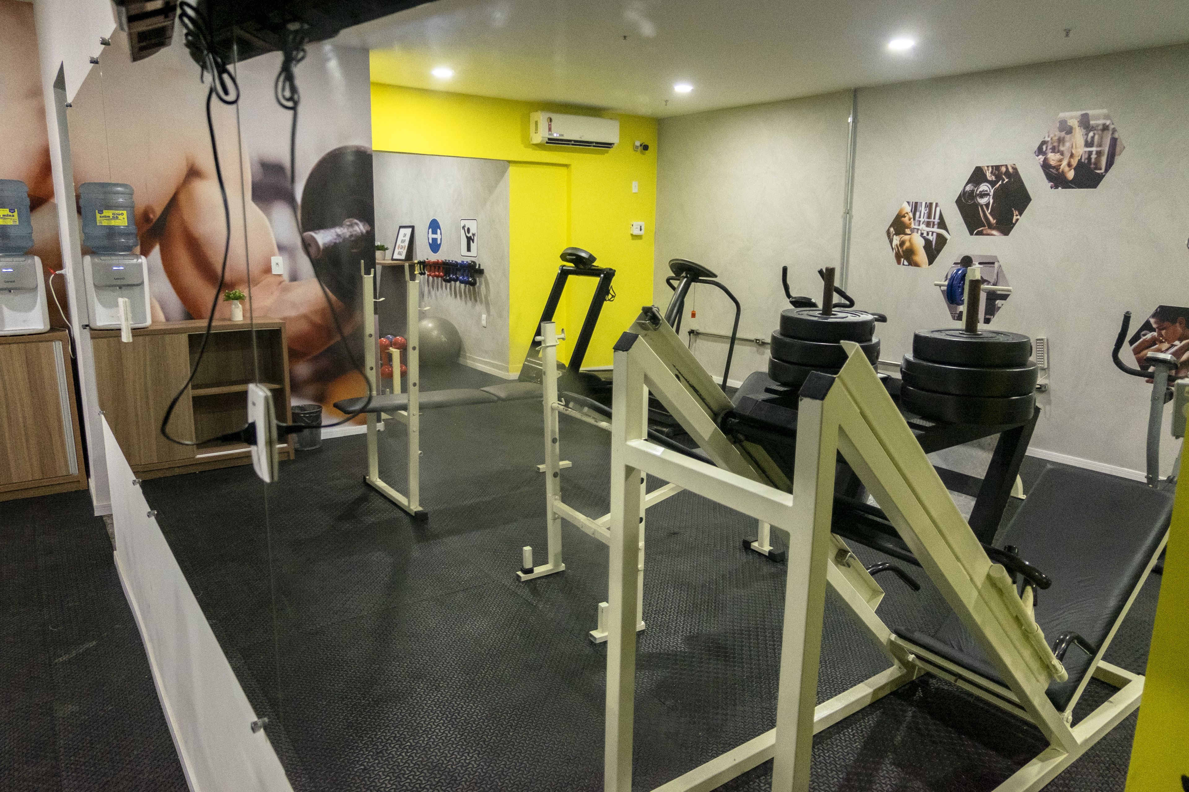 A gym with weightlifting equipment, a water dispenser, and a large poster on the wall.