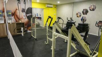 A gym with weightlifting equipment, a water dispenser, and a large poster on the wall.