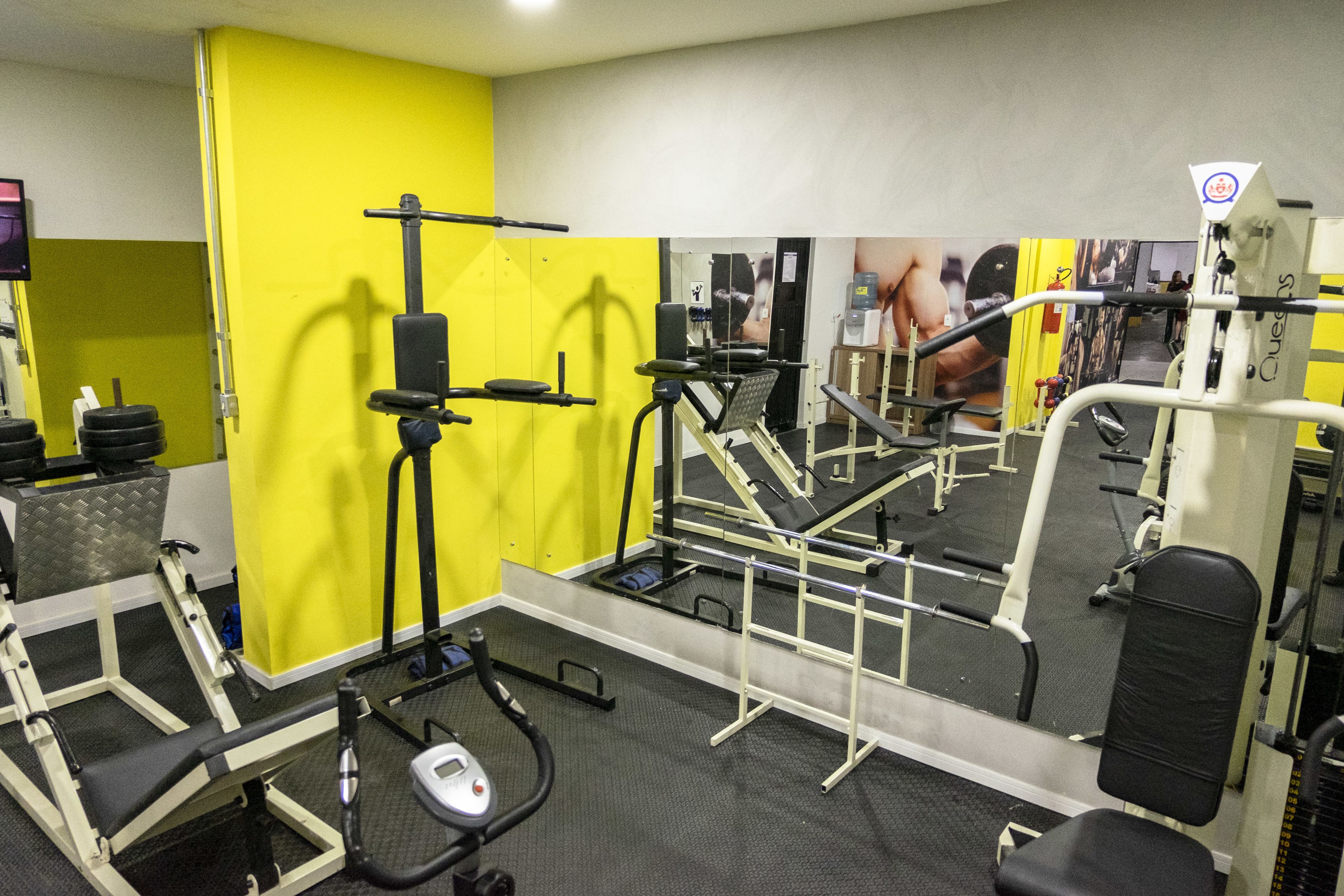 Une salle de sport équipée de divers appareils d’exercice, notamment un tapis de course, des appareils de musculation et un banc.