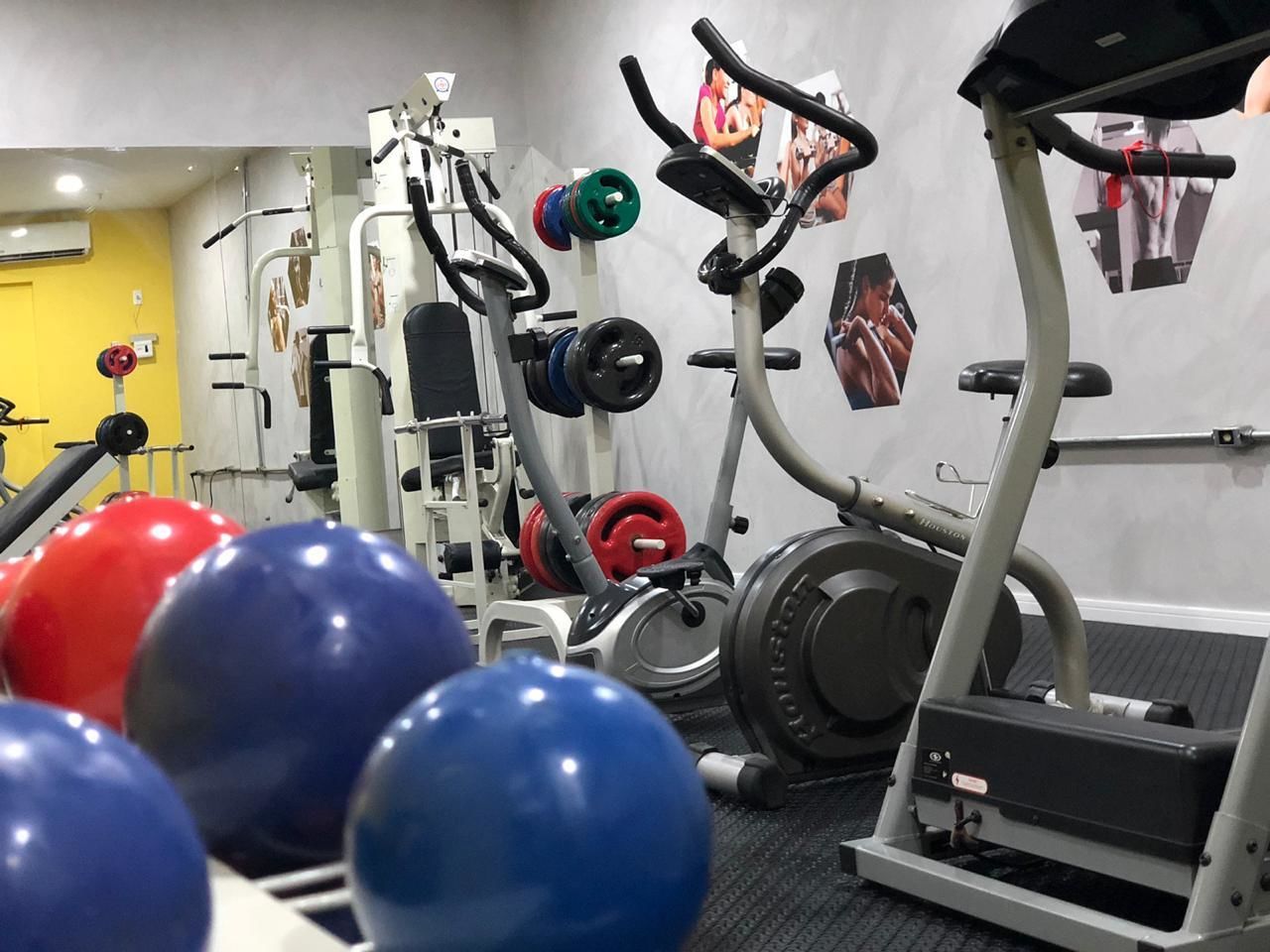 Une salle de sport équipée de matériel d’exercice, notamment un tapis de course, des appareils de musculation et des ballons d’exercice.