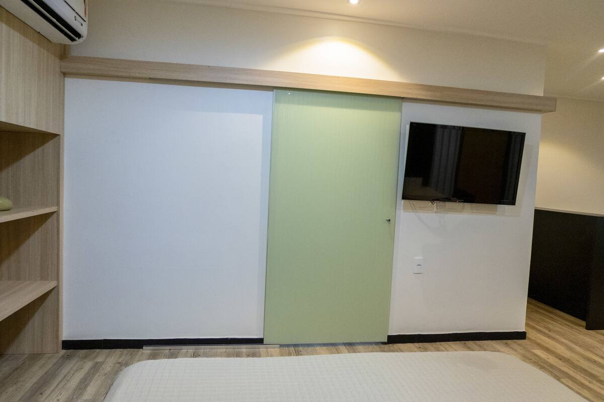 A room with a bed, a wardrobe, a television, and a shelf.