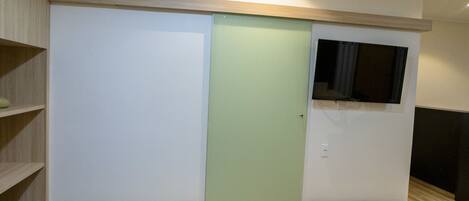 A room with a bed, a wardrobe, a television, and a shelf.