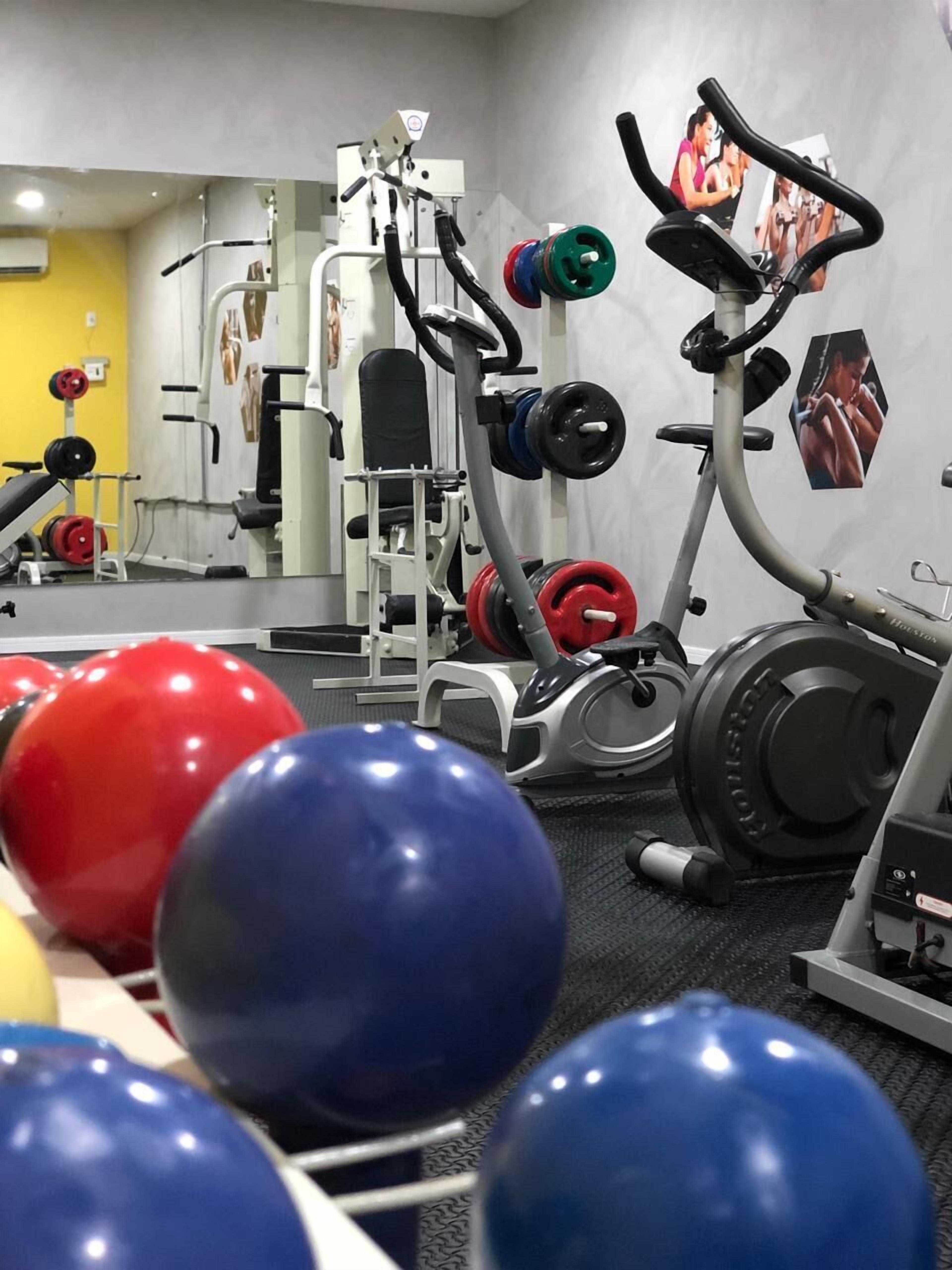 A gym with exercise equipment, weightlifting racks, and exercise balls.