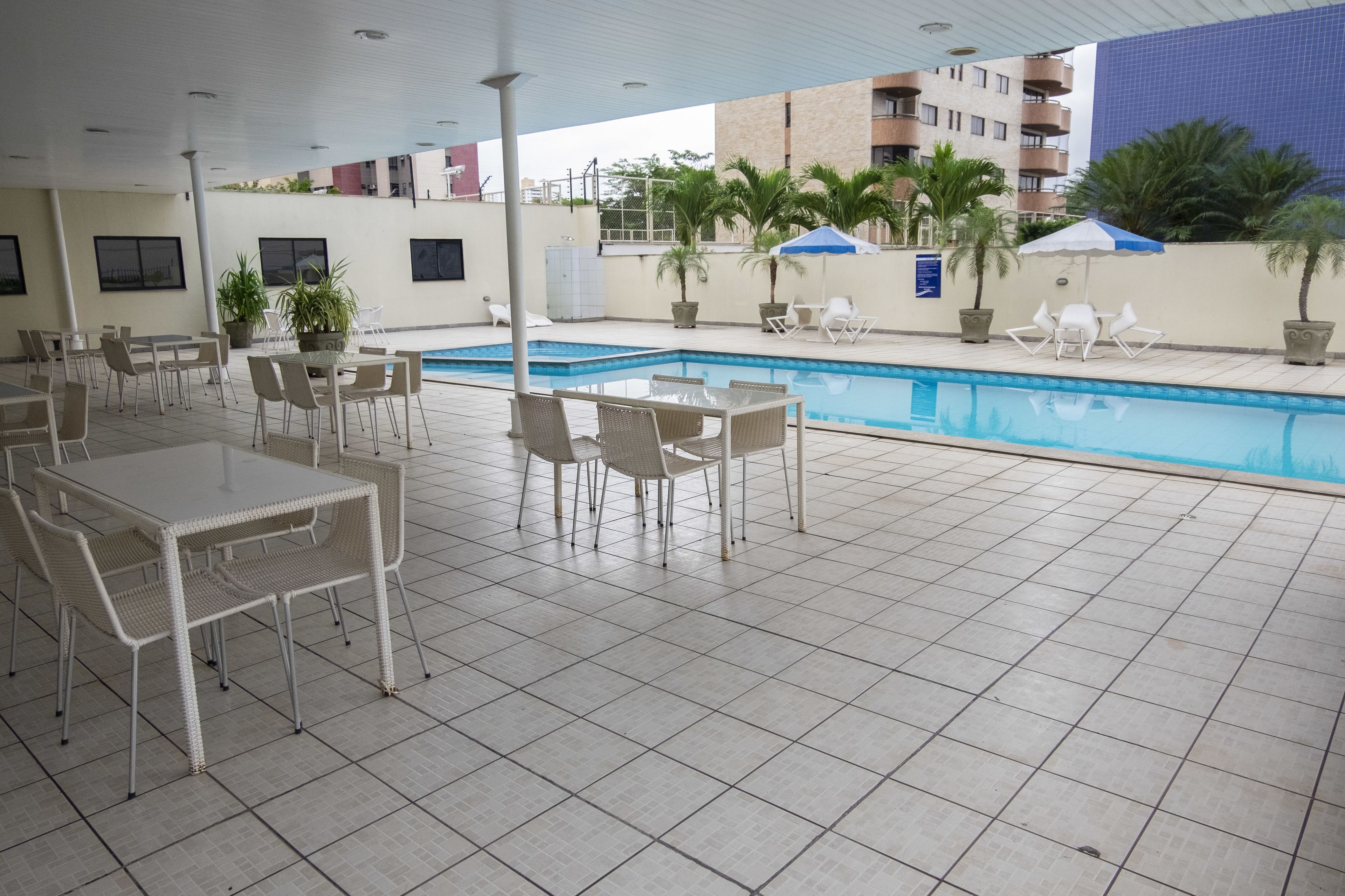 A poolside area with tiled flooring, outdoor seating, and a swimming pool.