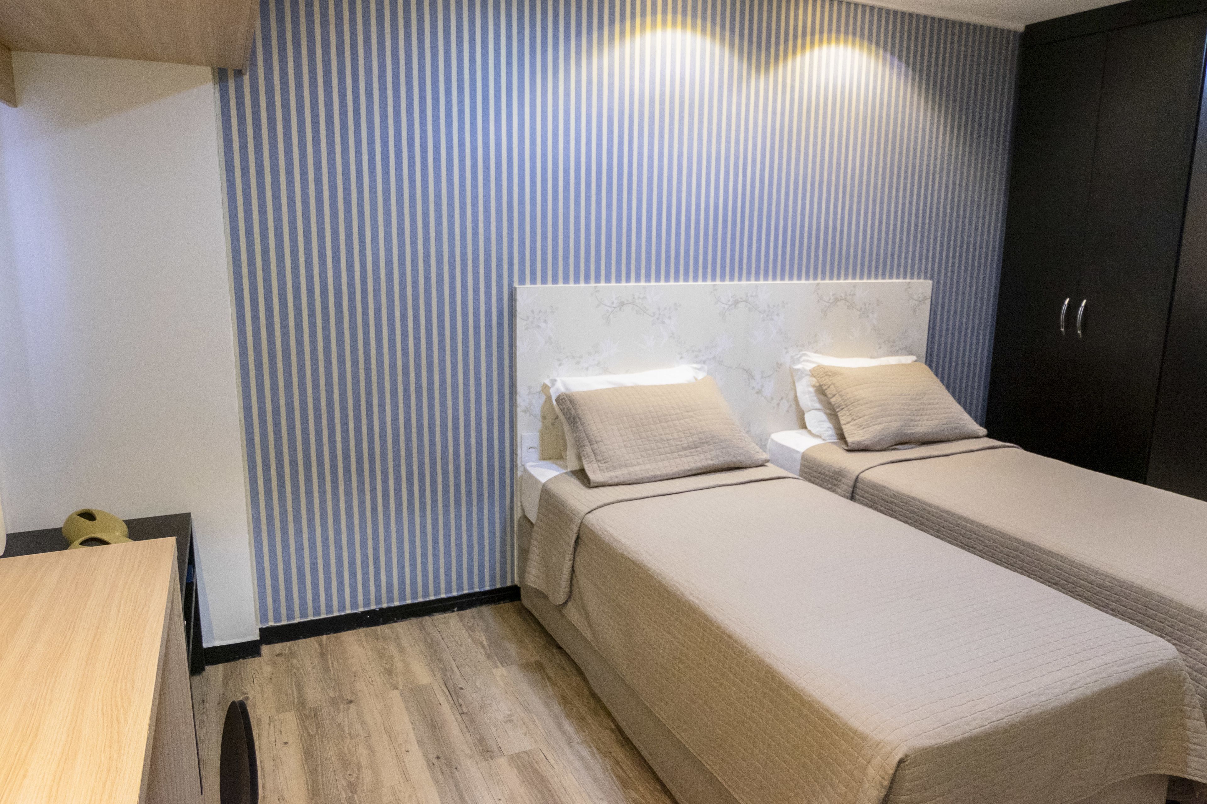 Una habitación con dos camas, un escritorio de madera y un armario.