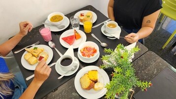 Una mesa dispuesta para una comida con varios platos, bebidas y una pequeña planta.
