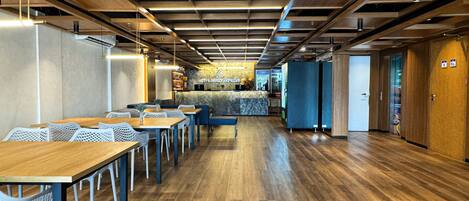 Un vestíbulo de hotel moderno con suelo de madera, un mostrador de recepción, zona de estar y un bar.