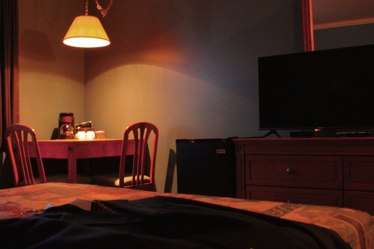Una habitación de hotel con cama, escritorio con lámpara, televisión y cómoda.