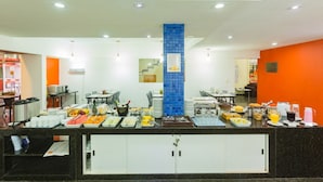 A buffet setup with various food items and beverages, a blue tiled column, and a counter with a black granite surface. - Arrey Fórmula Hotel - Teresina (Teresina)