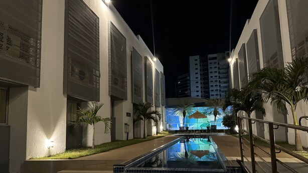 A nighttime view of a hotel with a swimming pool, palm trees, and a mural on the building. - Arrey Fórmula Hotel - Teresina (Teresina)