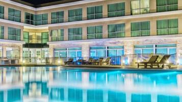 A hotel with a large outdoor swimming pool, multiple floors, and a modern architectural design.