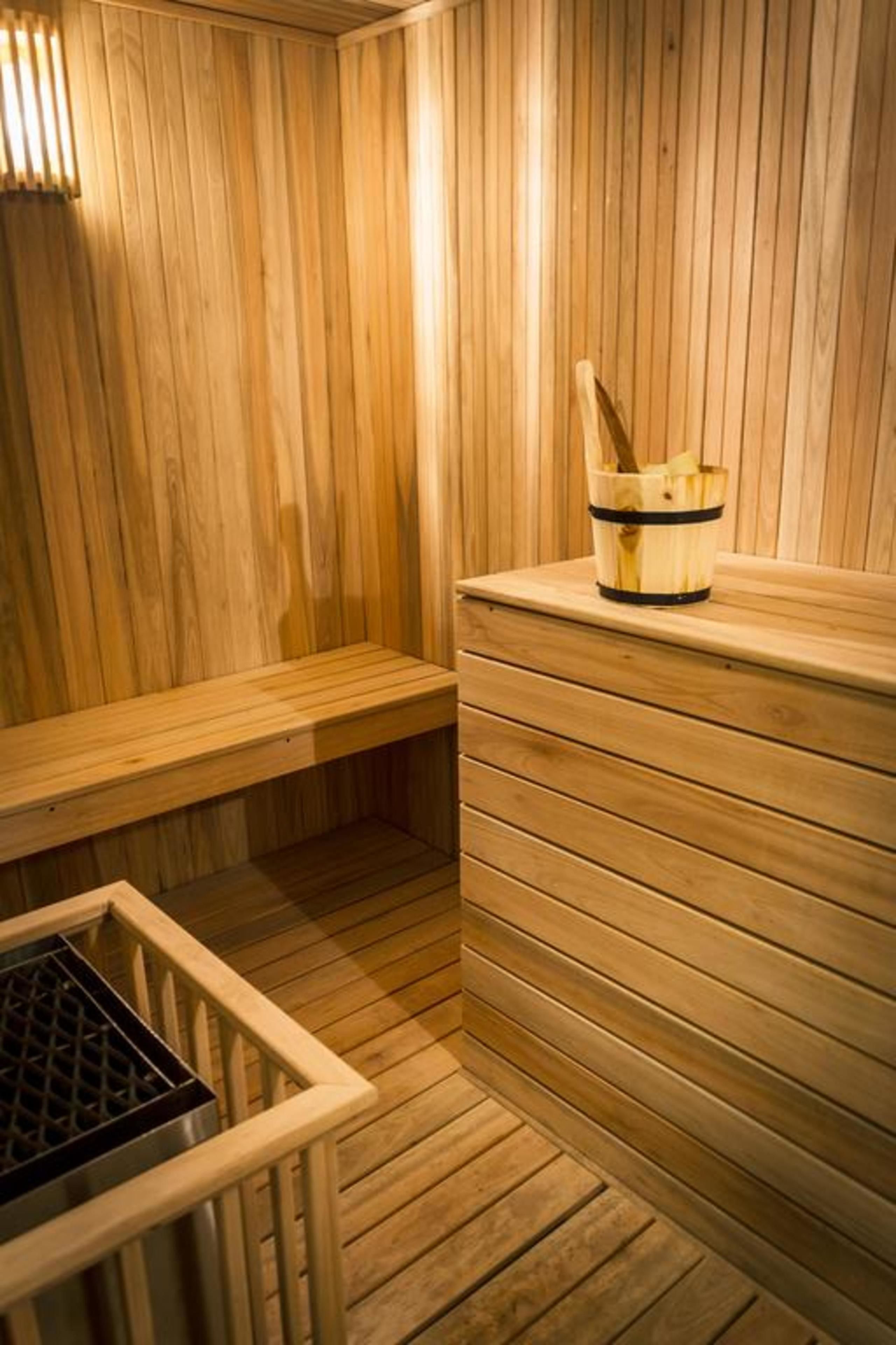 Una sauna de madera con bancos y un balde de toallas.
