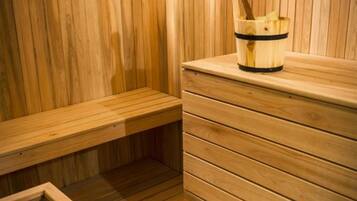 Una sauna de madera con bancos y un balde de toallas.