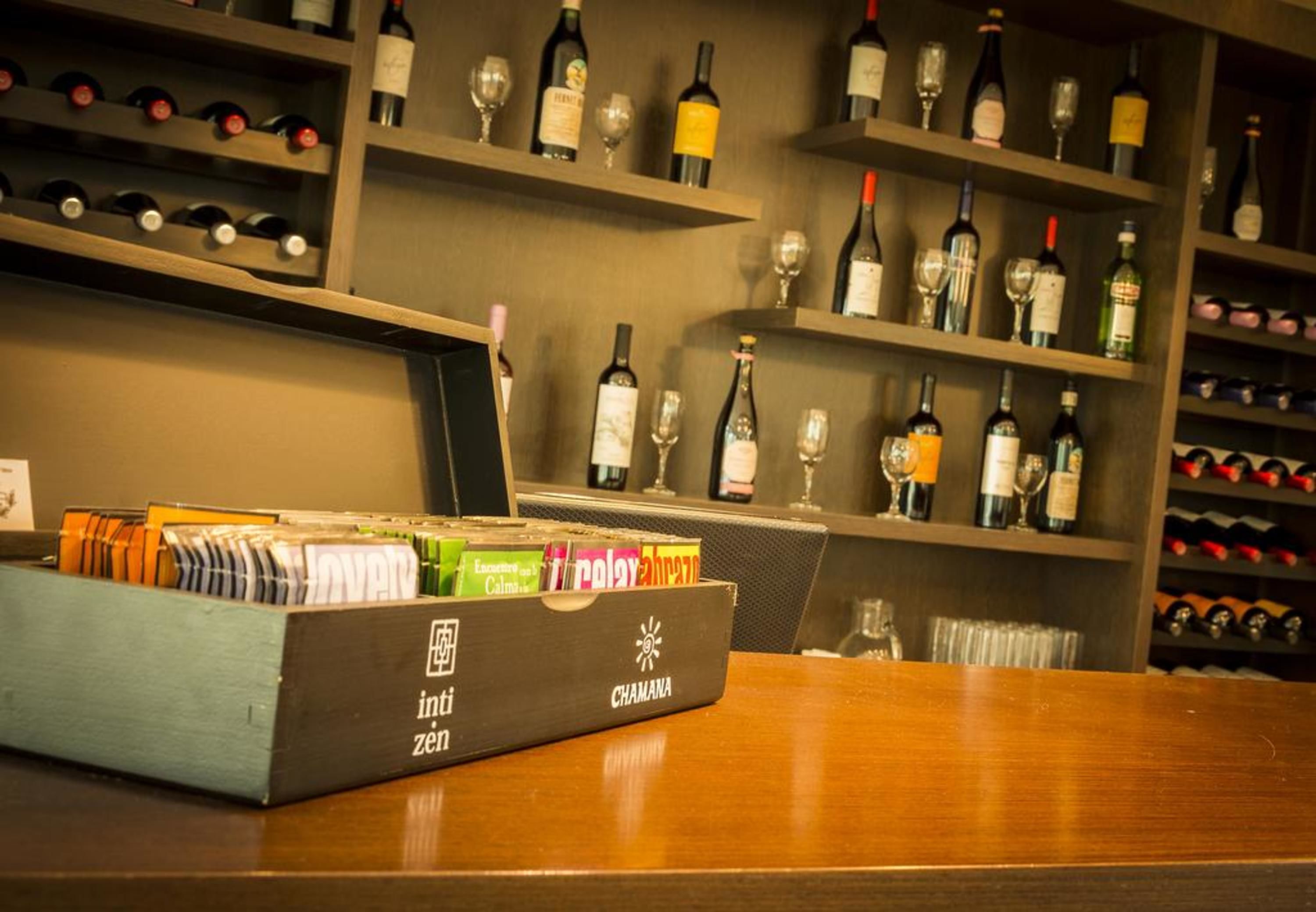 Zona de bar con estantes llenos de botellas de vino y copas, una barra de madera y una caja con la etiqueta 'int. zen'.