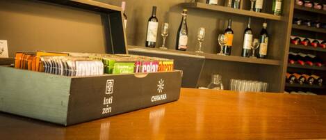 Zona de bar con estantes llenos de botellas de vino y copas, una barra de madera y una caja con la etiqueta 'int. zen'.