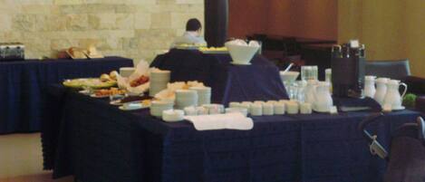 Una mesa de buffet con diversos platos y bebidas, frente a una pared de piedra.
