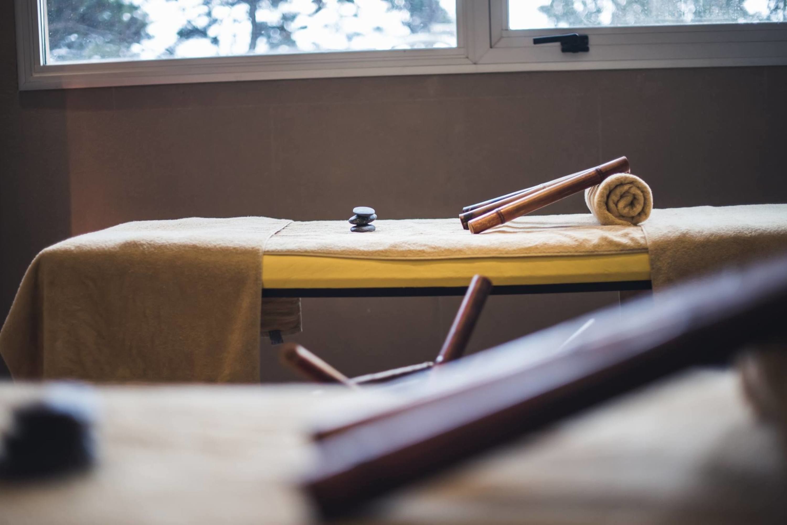 A room with a bed, a window, and a wooden object on the bed.