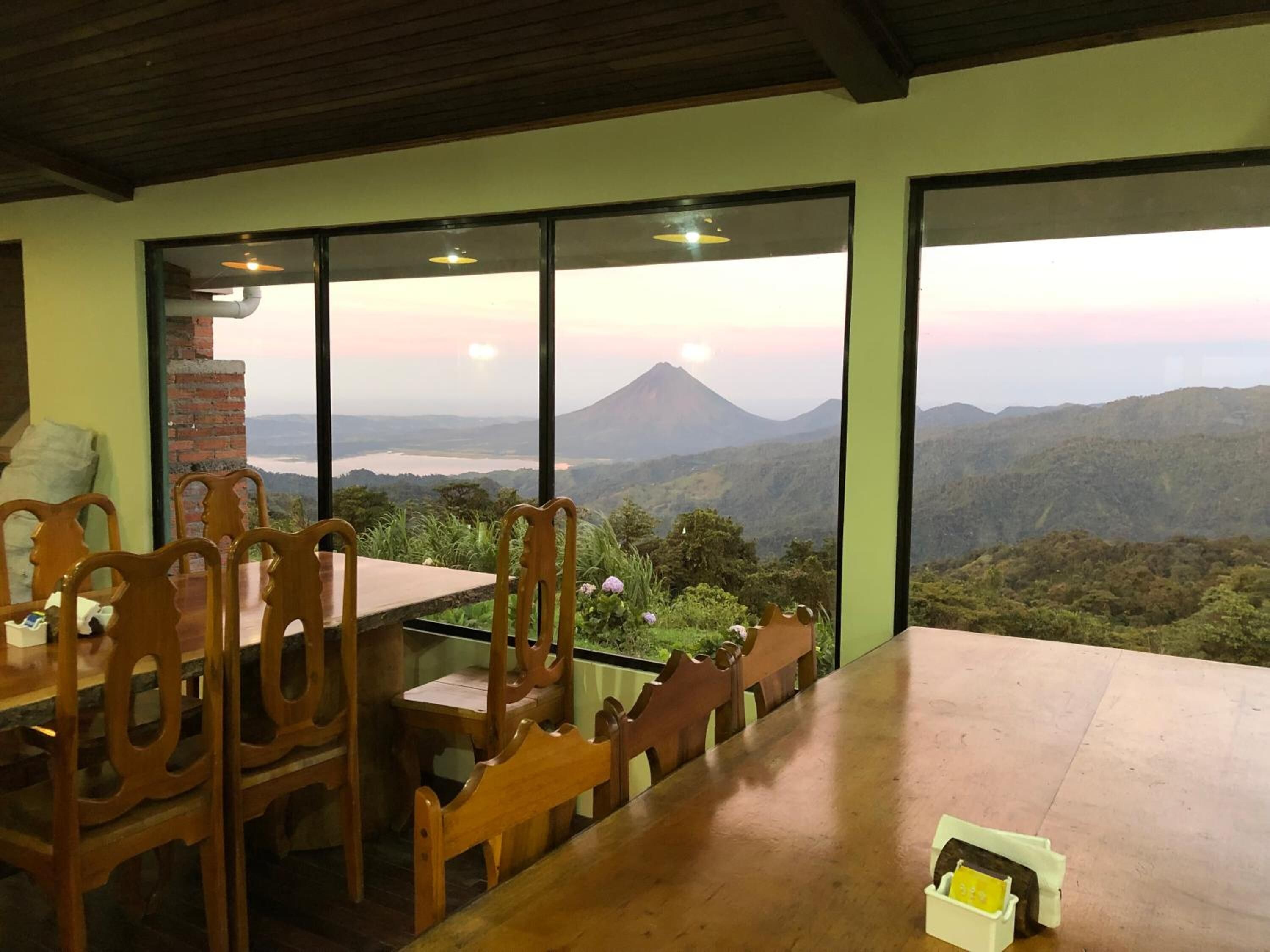 A dining area with a table and chairs, large windows offering a view of a mountainous landscape.