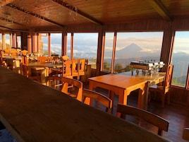 Un restaurante con muebles de madera y amplios ventanales que ofrecen vistas a la montaña.