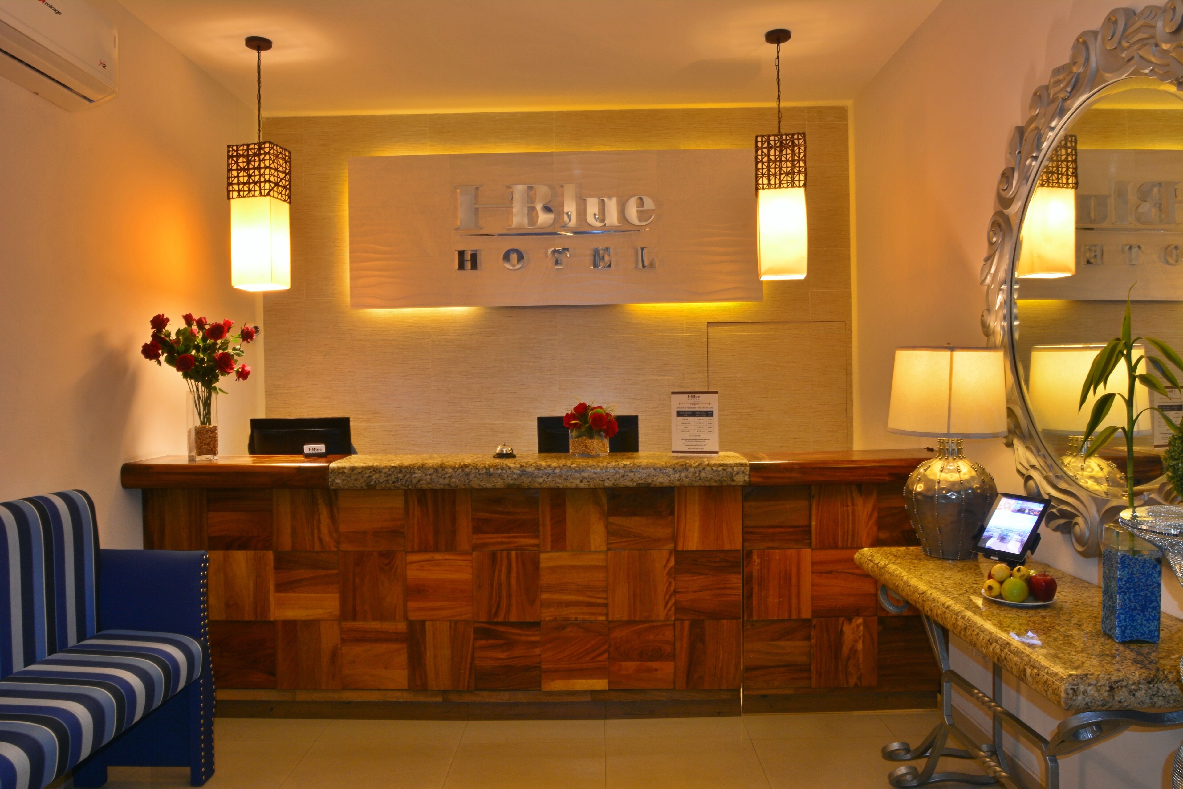 Zona de recepción de un hotel con un mostrador de madera, un sofá azul, un espejo y un cartel que dice "Blue Hotel".