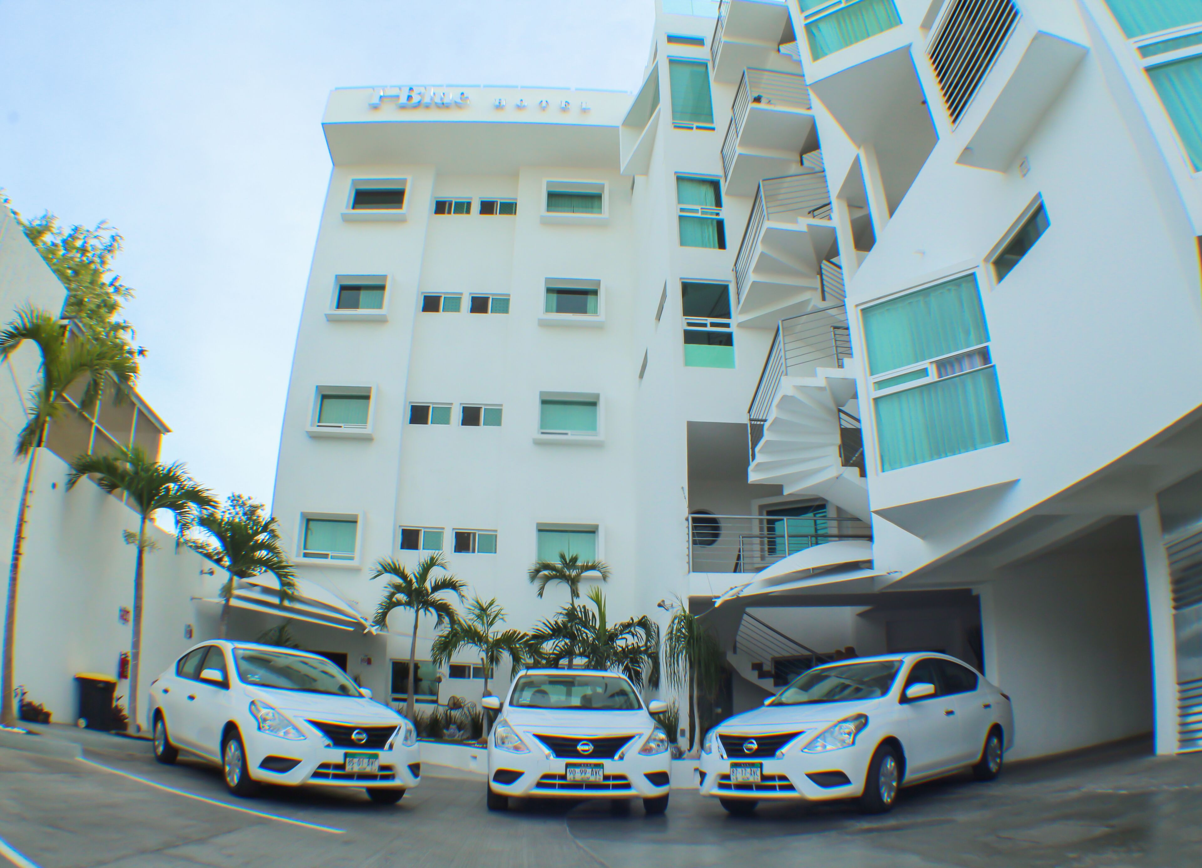 Un edificio moderno con tres coches blancos estacionados adelante.