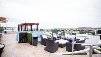 Terraza en la azotea con mobiliario exterior, piscina y vistas de la ciudad.