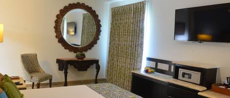 A hotel room with a bed, a desk, a television, and a mirror.