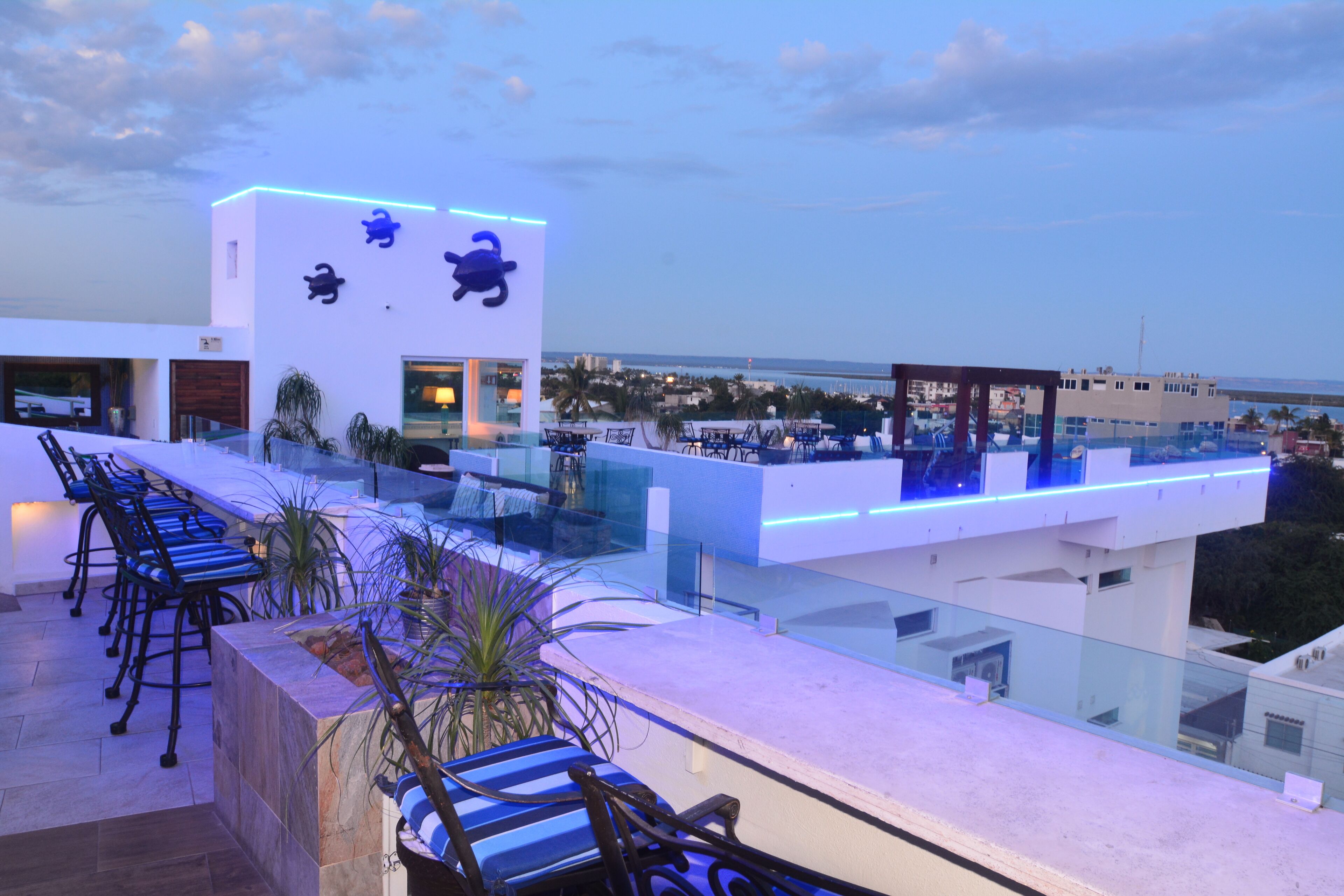 A rooftop bar with seating, a pool, and a view of the cityscape.