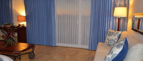 Una sala de estar con un sofá, una mesa de centro, una lámpara y un televisor montado en la pared.