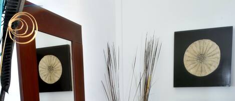 Un baño con un lavabo de vidrio, un espejo y dos marcos de cuadros colgados en la pared.