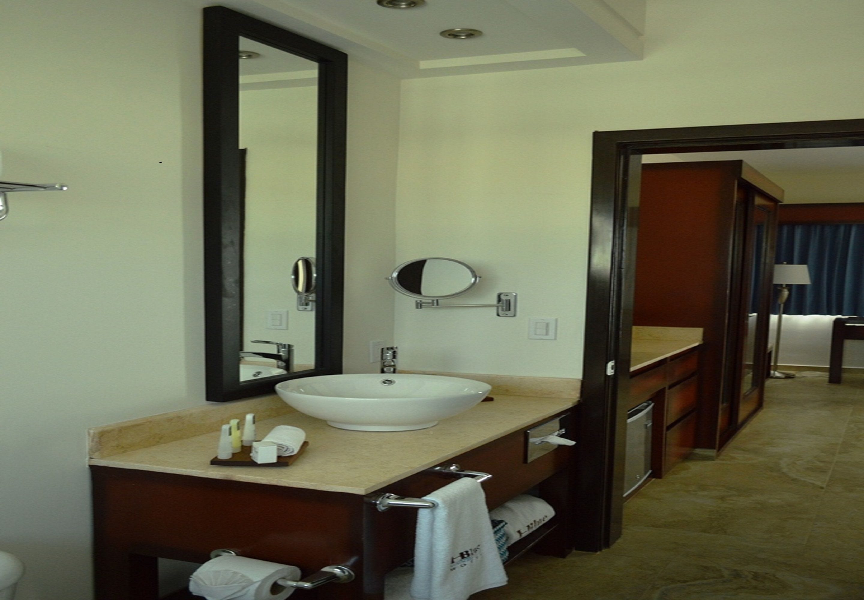 A hotel bathroom with a large mirror, a white sink, and a towel rack.