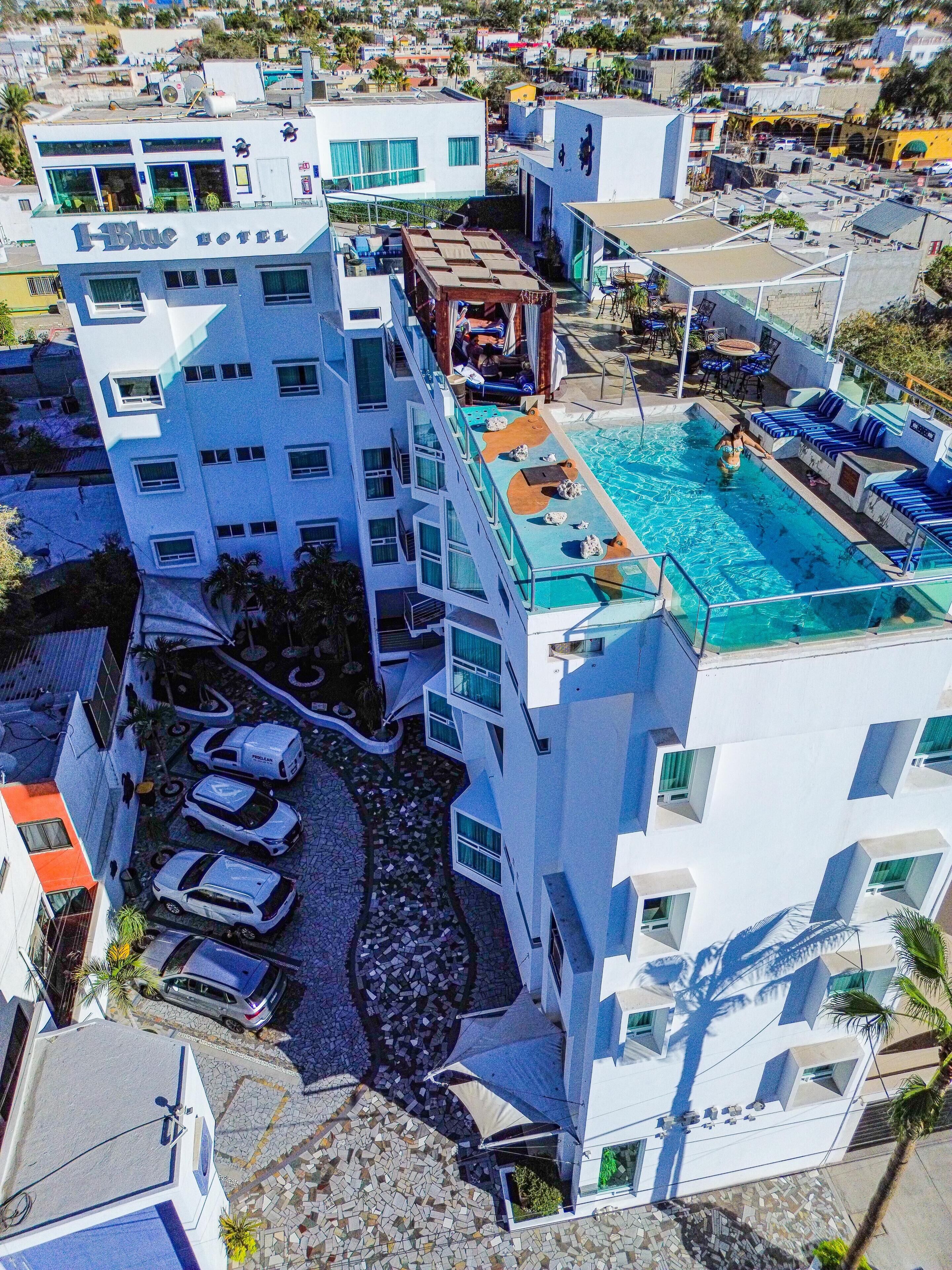 Un hôtel moderne doté d’une piscine sur le toit, de nombreux balcons et d’un espace de stationnement.