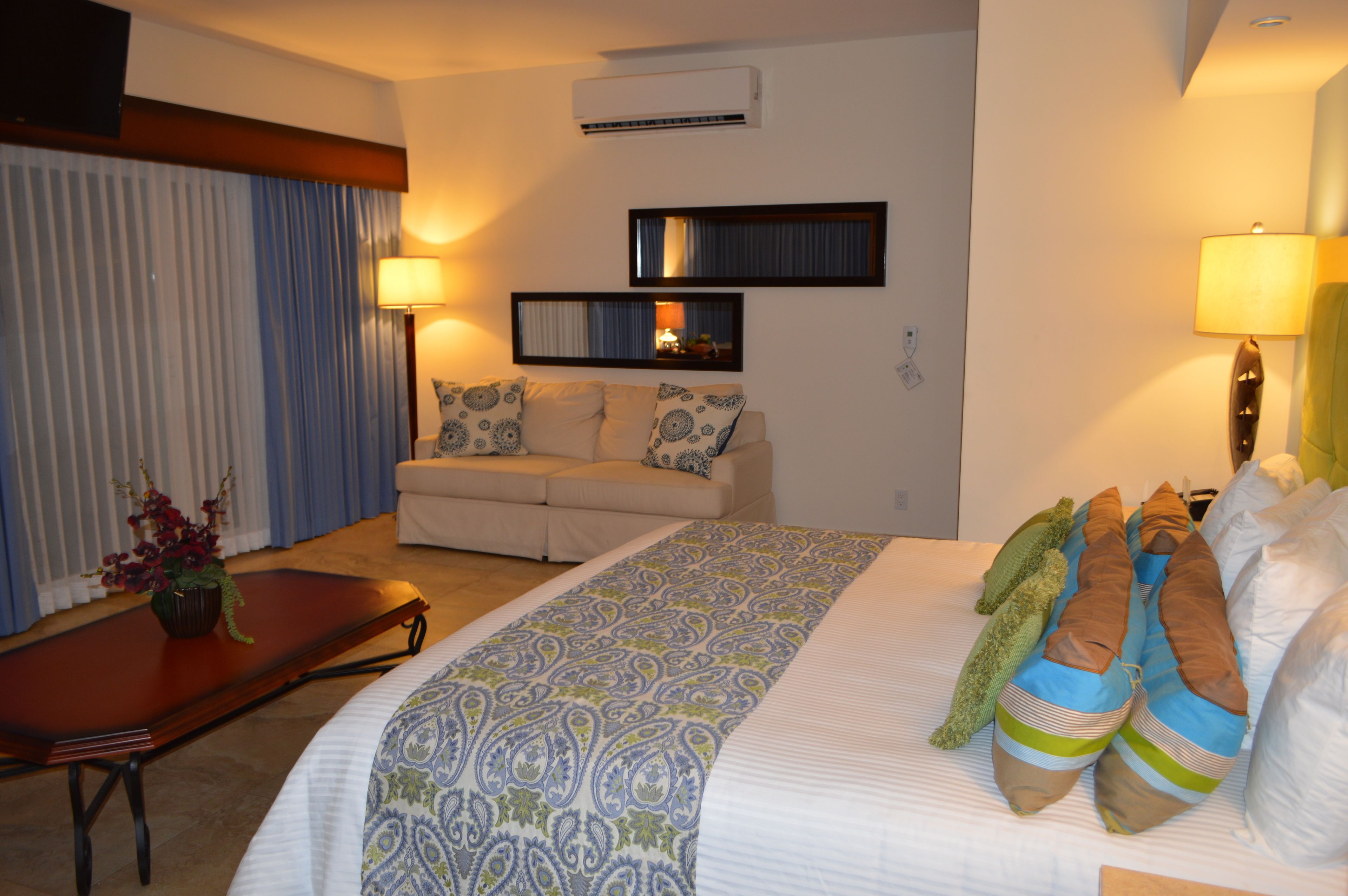 Une chambre d’hôtel avec un lit, un canapé, une petite table et un miroir au mur.