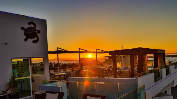 A rooftop terrace with seating and a view of the sunset. - Hotel HBlue Centro (La Paz)